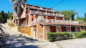 un grand bâtiment orange avec un palmier devant dans l'établissement Corfu Paloma Apartments, à Ýpsos