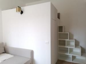 Habitación blanca con cama y estante para libros en BED and BIKE - BERGAMO Home Sweet Home, en Bérgamo