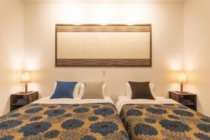 two beds sitting next to each other in a bedroom at Yukurina Resort Okinawa in Motobu