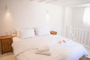 a bedroom with two beds with white sheets and white pillows at Mooi Boni's in Mikonos