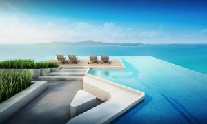 a swimming pool with chairs and the ocean at Andromeda Seaview Condo Near Beach in Pattaya South