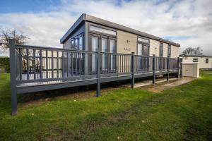 a small house with a balcony on the grass at Modern 6 Berth Caravan With Decking At Cherry Tree Park In Norfolk Ref 70324c in Great Yarmouth