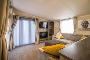 a living room with a couch and a television at Modern 6 Berth Caravan With Decking At Cherry Tree Park In Norfolk Ref 70324c in Great Yarmouth