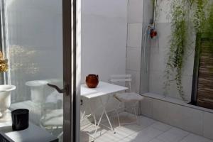 uma casa de banho com um chuveiro, uma mesa e cadeiras em El patio de Nervión. em Sevilha