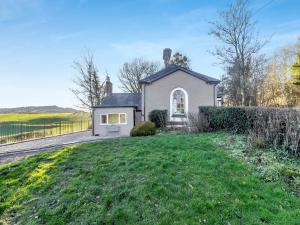 een klein wit huis met een grasveld bij The Lodge in Wonastow