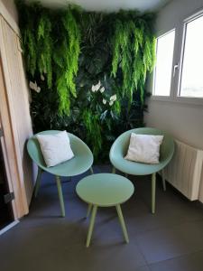 two tables and chairs in front of a green wall at Le Churchill Hôtel & Spa in Carnac