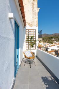 a chair on a balcony with a view of a city at Apartaments Bellaire Cadaqués in Cadaqués