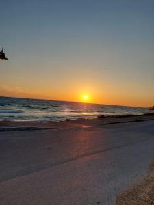 een zonsondergang op een strand met de oceaan bij Golden Horizon Haven in Preveza