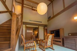 a living room with a staircase and chairs and a television at Shionoyu Onsen Rengetsu in Nasushiobara