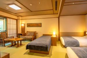 a hotel room with two beds and a table and chairs at Shionoyu Onsen Rengetsu in Nasushiobara