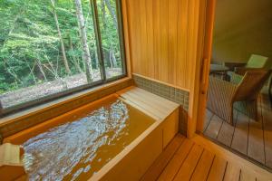 a hot tub in a house with a window at Shionoyu Onsen Rengetsu in Nasushiobara