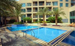 a large swimming pool with palm trees and a building at Icon Casa Living - Downtown Burj Views Towers in Dubai