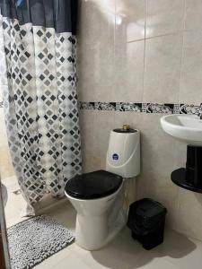 a bathroom with a toilet with a black seat and a sink at Apartamento a 5 minutos del parque principal in Jardin