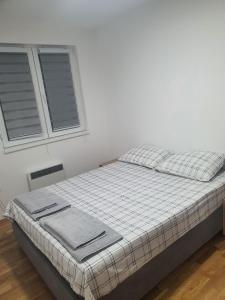 a bed in a white room with two windows at N&M Apartment in Pirot