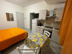 a kitchen with an orange bed and a table and chairs at Le Camere Del Villaggio in Agrigento +39 photos
