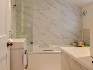 a white bathroom with a tub and a sink at Sunnyside in West Mersea