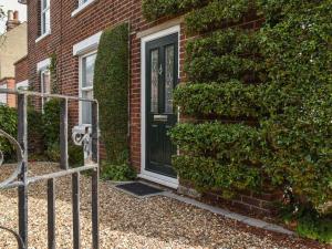 a brick house with a black door and ivy at Sunnyside in West Mersea