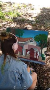 a girl wearing headphones looking at a painting of a house at Dva lava in Podaca