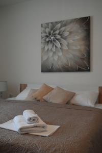 ein Handtuch auf einem Bett mit einem Bild an der Wand in der Unterkunft Apartman Ariana in Selce