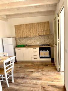 una cucina con armadi bianchi, tavolo e frigorifero di Villa Zaffiro a Lampedusa