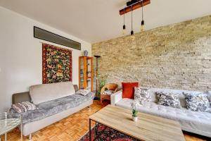 a living room with two couches and a brick wall at Grand appartement calme à 30 min de Paris in Morsang-sur-Orge