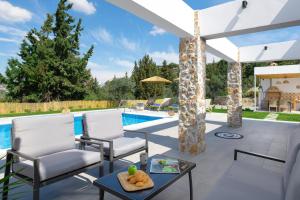 een patio met 2 stoelen en een tafel naast een zwembad bij Aiora Luxury Villas in Afantou