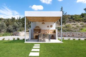 a pavilion with a table and chairs in a yard at Aiora Luxury Villas in Afantou
