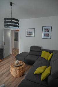 ein Wohnzimmer mit einem schwarzen Sofa und gelben Kissen in der Unterkunft Apartman Ariana in Selce