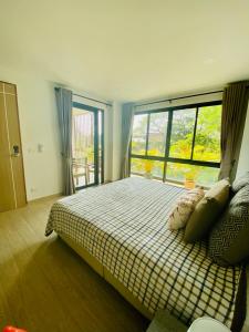 een slaapkamer met een bed en een groot raam bij Bann Chidtha family suite full kitchen near Suvarnabhumi Airport in Bangkok