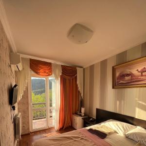 um quarto com uma cama e uma grande janela em Гостевой дом Марина em Gagra