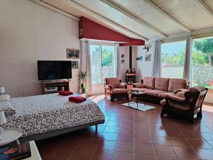 a bedroom with a bed and a couch and a tv at Villa Manzella piscina privata in Cinisi