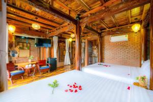 Eco Wooden villa Hoi An في هوي ان: غرفة نوم مع سرير مع زهور حمراء عليه