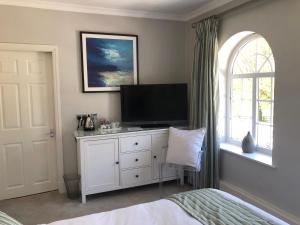 een slaapkamer met een televisie op een dressoir met een raam bij Room in Twemlow Green in Goostrey