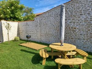 una mesa de picnic y dos sillas en un patio en La Grange 3 étoiles - Maison d'hôte à 10 min des plages, en Thairé