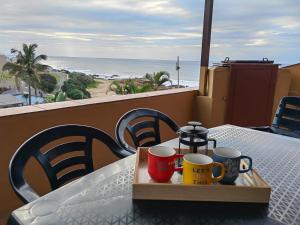 a tray with mugs on a table with a view of the beach at Villa del Sol Margate in Margate