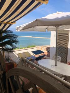a patio with a table and an umbrella and the ocean at Anzio a picco sul mare! in Anzio