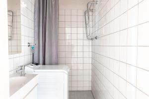 uma casa de banho em azulejos brancos com um lavatório e um chuveiro em 2ndhomes 1BR Apartment in the Center of Helsinki em Helsinque