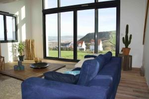salon z niebieską kanapą i dużymi oknami w obiekcie Villa vue exceptionnelle sur le Cap Gris-Nez w mieście Audinghen