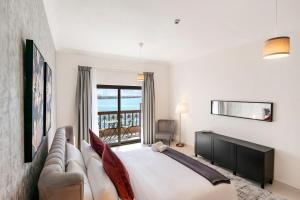 a bedroom with a bed and a couch and a window at FAM Living - Sarai Apartments - Private Beachfront Escape in Palm Jumeirah in Dubai