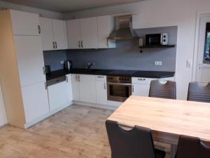 a kitchen with white cabinets and a wooden table at Ferienhäuser Eggers in Bispingen