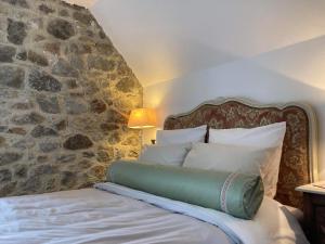 een slaapkamer met een bed met een stenen muur bij Gîte des Pommiers in Le Fresne-Poret