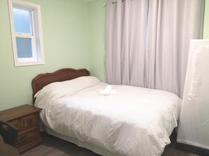 a bedroom with a white bed with a window at Countryroad Cozy 2Bedrooms suite2 in Nanaimo