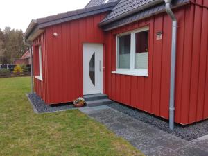 a red shed with a white door and a window at Ferienhaus Eggers in Bispingen