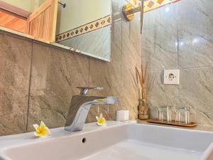 La salle de bains est pourvue d'un lavabo avec robinet et de fleurs. dans l'établissement Skywatch cottage, à Klungkung