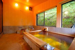 a large bath tub in a bathroom with two windows at Kurasako Onsen Sakura in Minamioguni