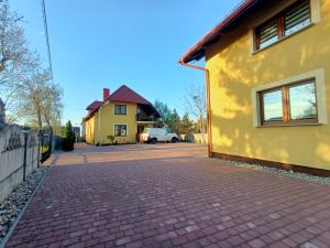 ジェロナ・グラにあるNoclegi Zielona Góra u Moniの黄色い家の前のレンガ道