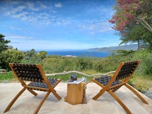 duas cadeiras e uma mesa com vista para o oceano em U Castellu Chambres d'hôtes & Location villa et appartements vue mer em Propriano