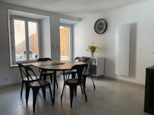 a dining room table with chairs and a clock on the wall at Maison avec cour privative in Luz-Saint-Sauveur