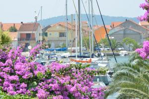 a group of boats docked in a harbor with pink flowers at Apartment Velika obala in Bibinje