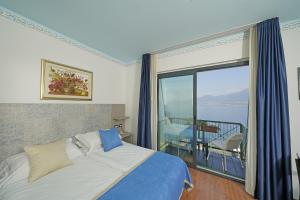 a bedroom with a bed and a large window at Hotel Villa Carlotta in Torri del Benaco